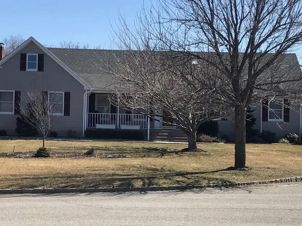 Selling a house after a life change in Riverhead: gray cape with a front porch and bare trees