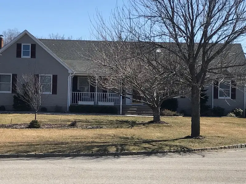 Gray cape with a front porch and bare trees, Riverhead, NY