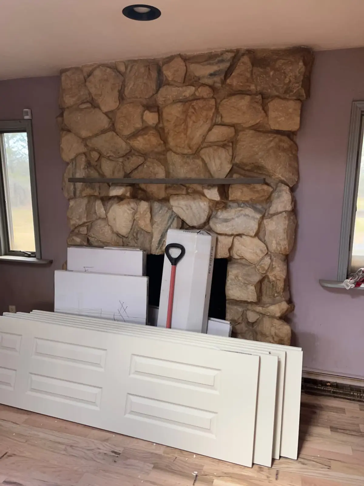 Selling a house with multiple heirs in Riverhead: new interior doors stacked by the stone fireplace