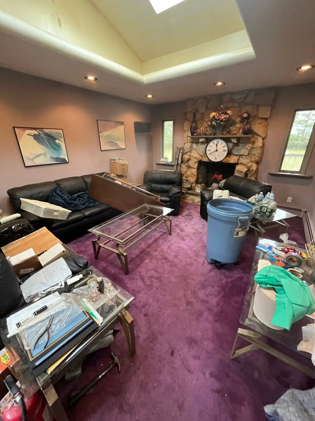 Selling estate property as an executor in Riverhead: purple carpeted room with a stone fireplace and clutter