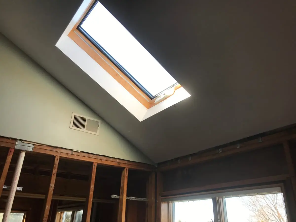 Selling a fire-damaged house in Riverhead: vaulted bedroom with a skylight and open studs